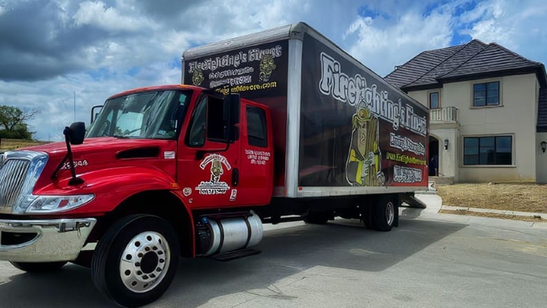 Red and black moving truck parked in front of a house facing the street