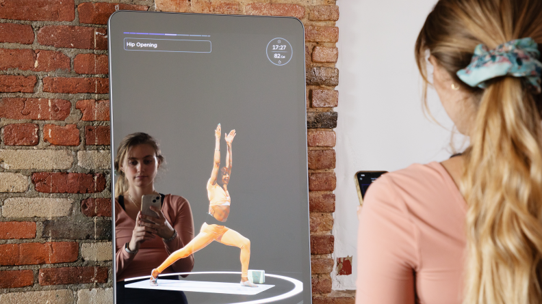 A woman taking a yoga class with the Fiture workout mirror.