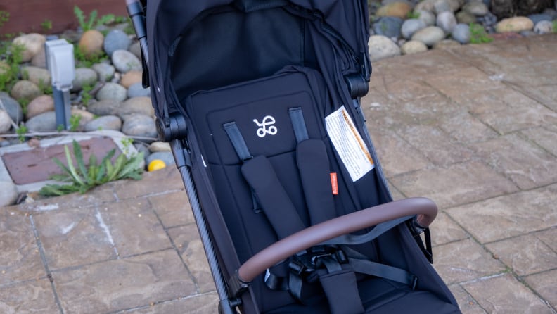 Close-up view of black Mamazing stroller clearly displaying shoulder straps and lap bar on a patio.