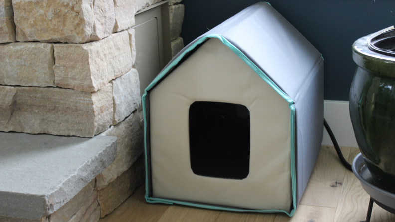 The Frisco Heated Cat House set up in the corner of a living room.