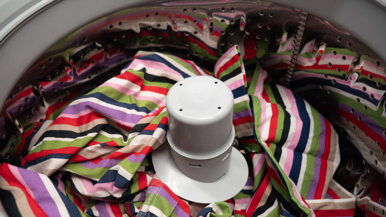 A close-up of the drum of the Frigidaire FFTW4120SW washing machine, which features an iridescent comforter that adds a sense of scale and a pop of color.  The comforter takes up most of the drum, although the pole agitator can still be seen poking outwards.