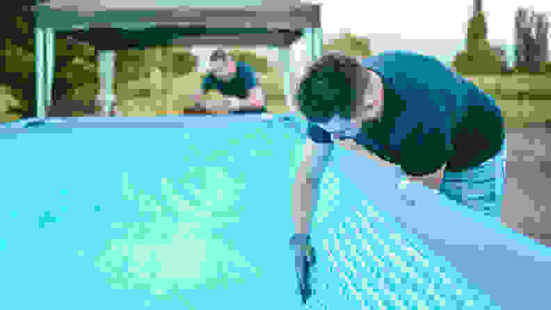 Two men setting up an inflatable above-ground swimming pool.