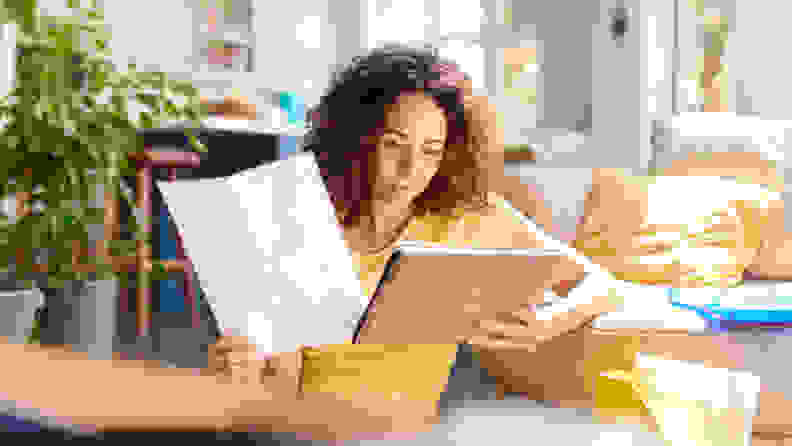 A woman reading a warranty while using a tablet.