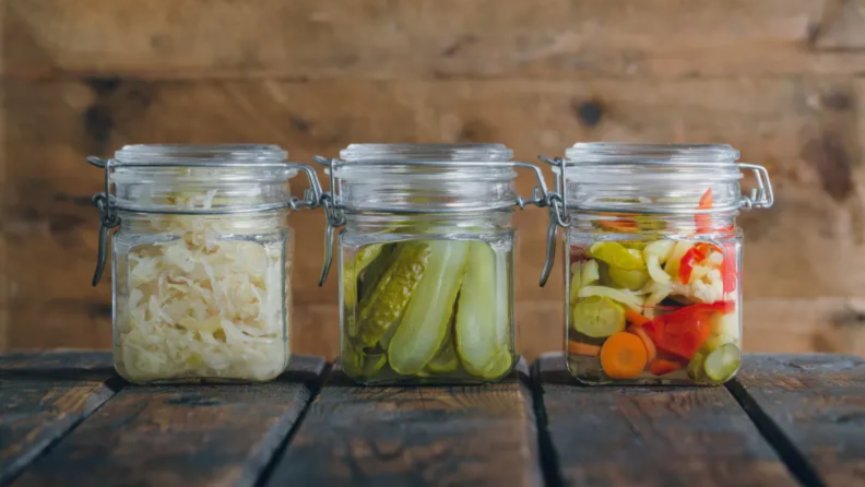An image of three jars of pickled vegetables and greens.
