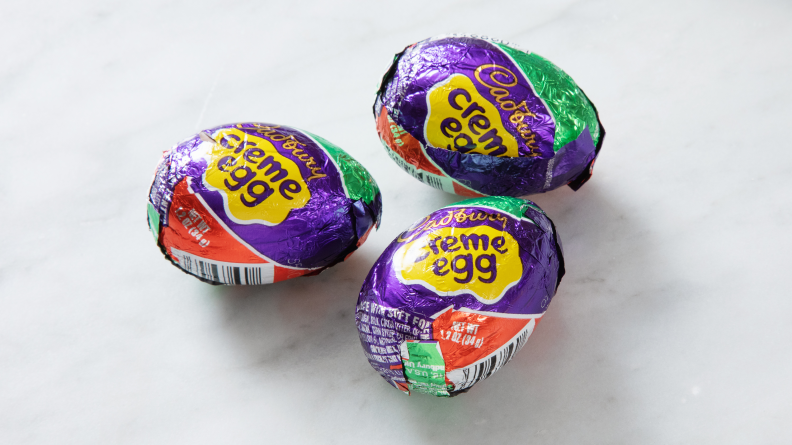 Three Cadbury creme eggs on white marble