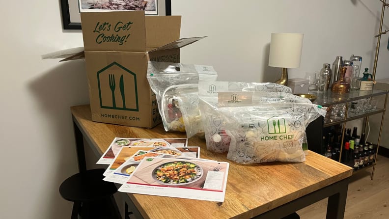 An open Home Chef box and bags of meal kits on a table