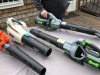 A person holds a cordless leaf blower while three others sit on a table