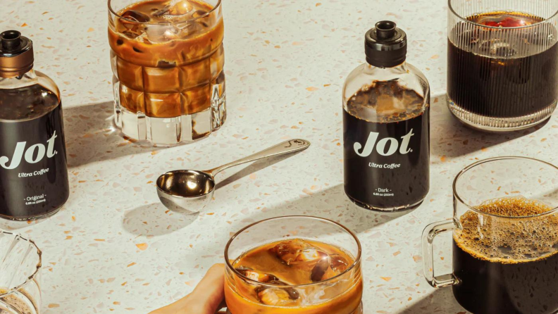 Jot bottles and glass of iced coffee on a white surface