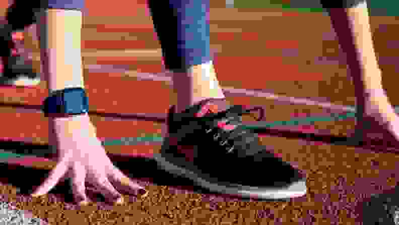 A tight shot of a person wearing Nike running shoes on a track.