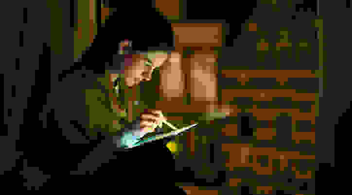 Woman using tablet and stylus in the dark