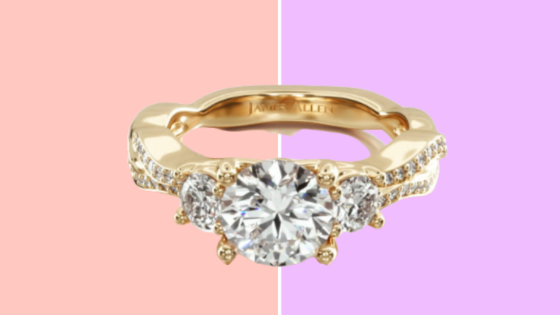 A gold diamond ring with a round diamond in the center and two smaller diamonds on either side.