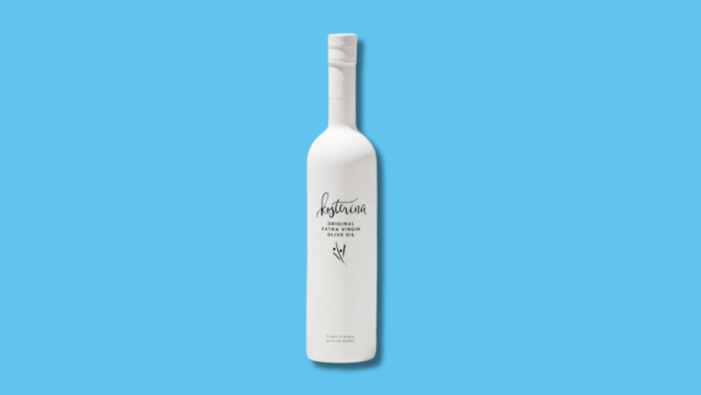 Slim, white rectangular bottle of Kosterina Original Extra Virgin Olive Oil in front of blue background.
