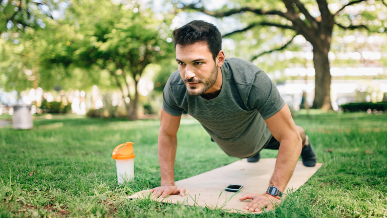 A man on a yoga mat in a park.