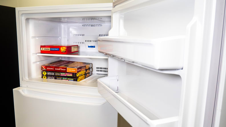A shot of the Frigidaire FFTR1814VW top-freezer refrigerator's freezer door and interior. The interior has some frozen pizza boxes stacked up inside, for scale.