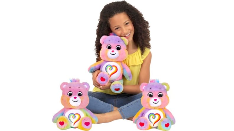 Child smiling while holding colorful stuffed bear.