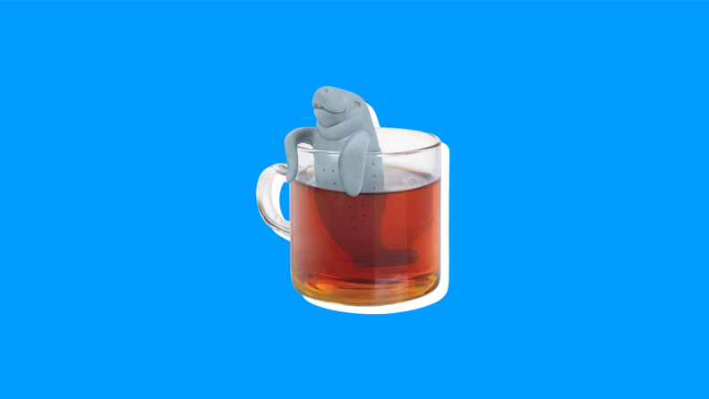 A Manatea Tea Infuser inside a cup of tea on a blue background.