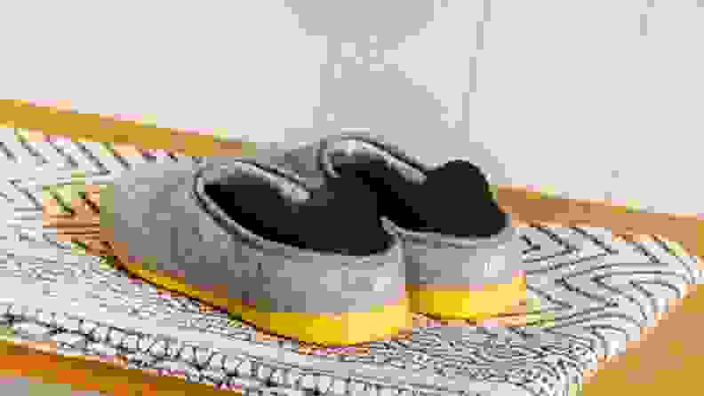 The backside of a pair of Mahabis Classic Men's Slippers, showing off yellow soles and logo.