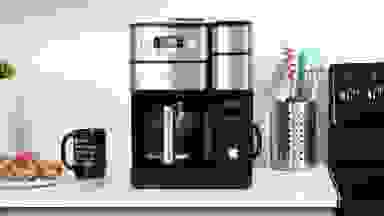 The Cuisinart coffee machine sitting on a kitchen counter beside a mug and pastries