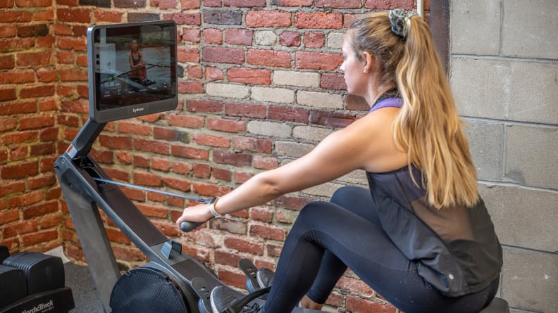 A person exercises using the Hydro Wave rower.