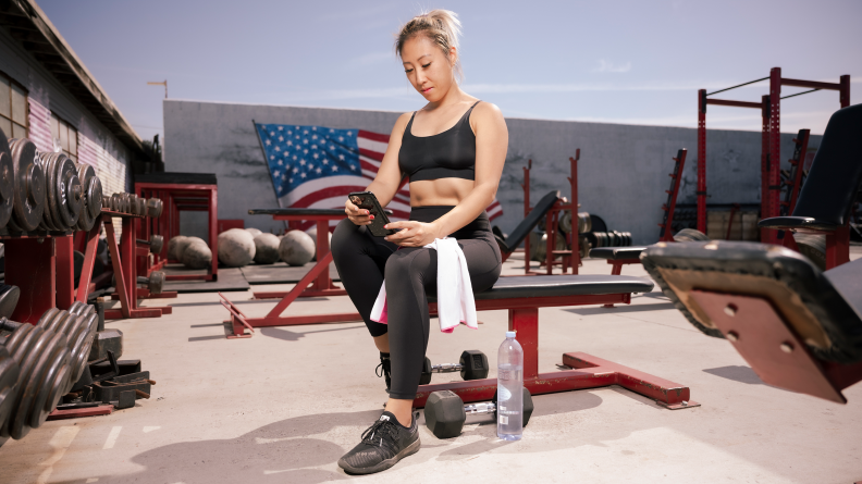 Person holding smartphone in hand with fitness tracker on wrist.