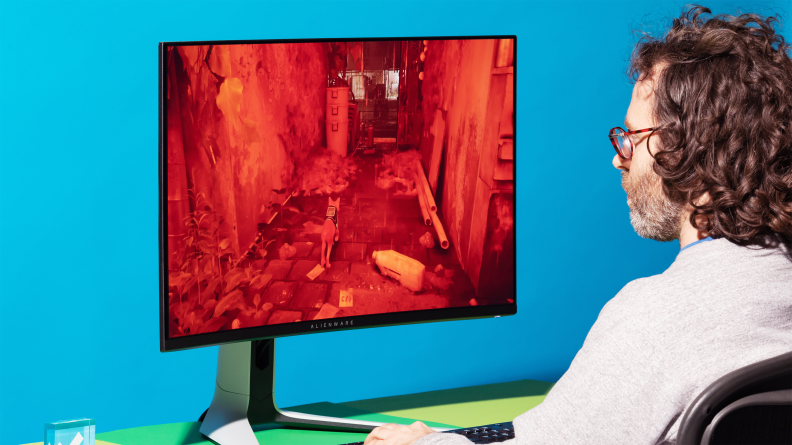 A man sitting in front of a 32 inch gaming monitor