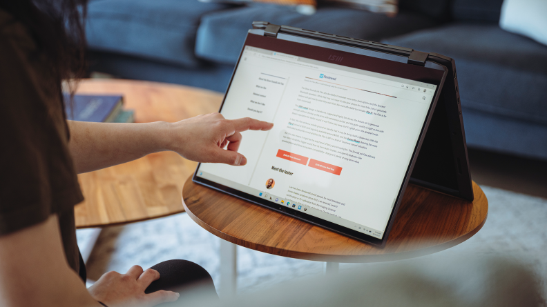 A person uses a touchscreen on a laptop.