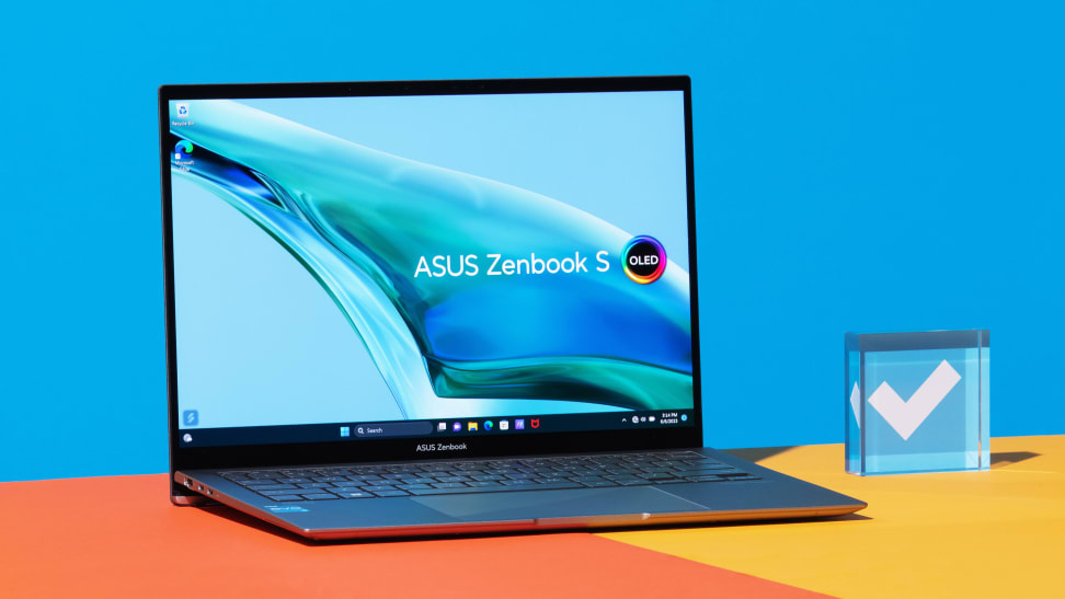 The Asus Zenbook S 13 OLED (2023) on an orange table with a blue background.