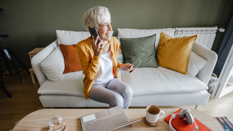 Senior woman talking on cellphone while on couch at home.