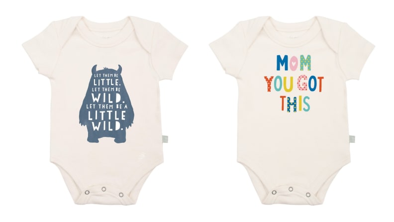 Two cream baby onesies with colorful writing printed on front.