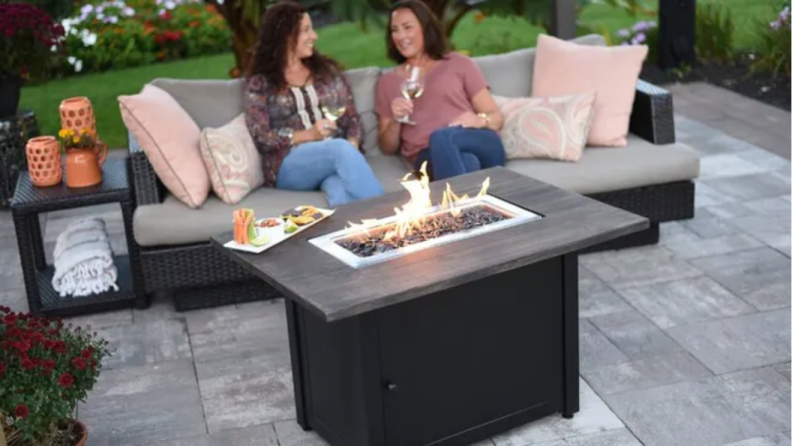 Two women sitting outside next to an Endless Summer Propane Fire Pit.