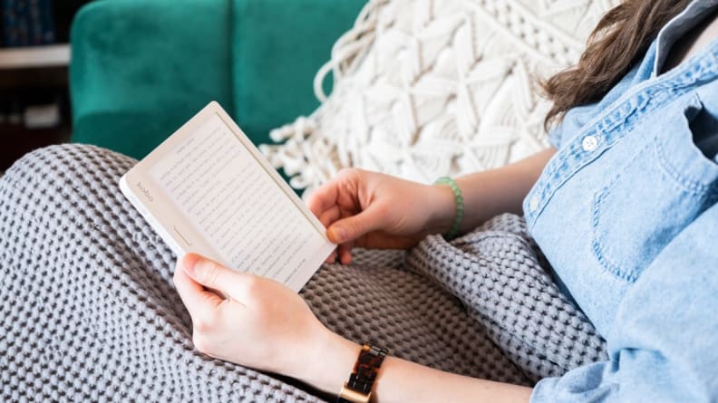 A person holding a Kindle in their lap and reading it