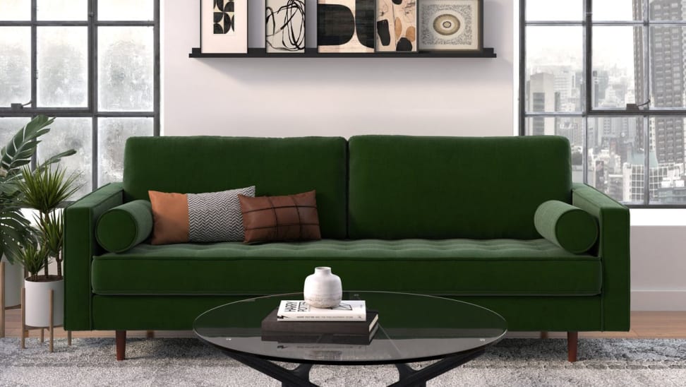 Dark green suede couch against a gray wall