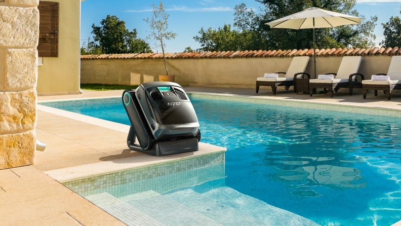 Piper X1 cordless robotic pool cleaner sits on the left side of an outdoor pool