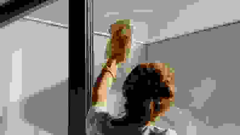 View from behind a woman wiping down a clear window.