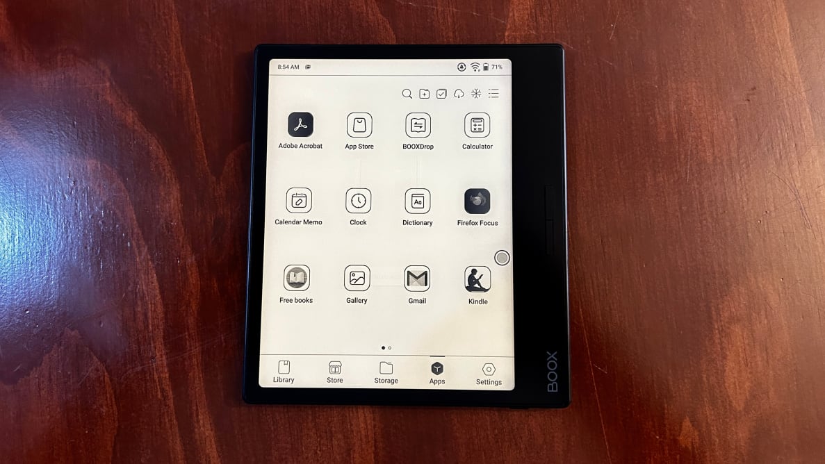The Onyx Boox Page e-reader sits on top of wooden surface with black and white screen display turned on.