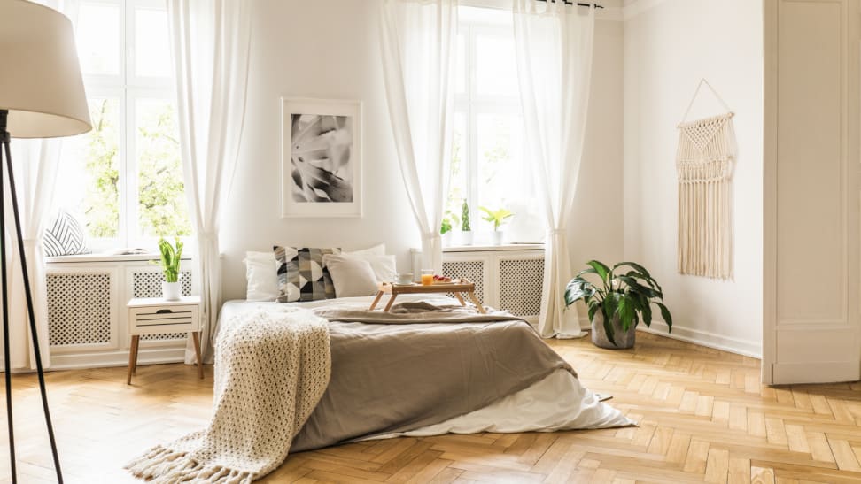 A white bed sits in the middle of a bright, sunny bedroom