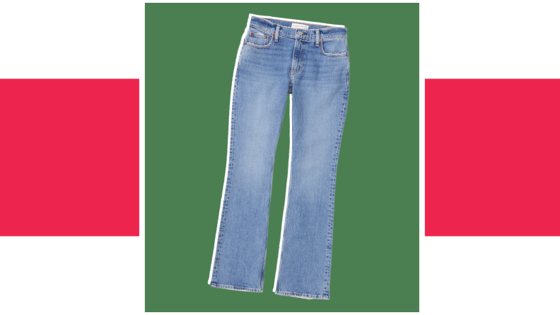 A pair of loose light-wash low-rise jeans against a green background.