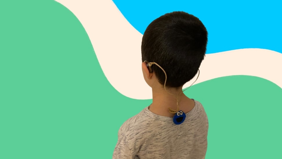 Small child wearing hearing aid clips around neck and in ears.