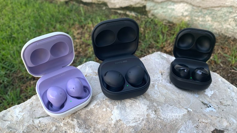 The Samsung Galaxy Buds 2, Galaxy Buds 2 Pro, and Galaxy Buds Pro sit in their open cases on a white rock.