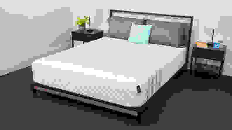 A mattress in a bedroom with bedside tables on either side.