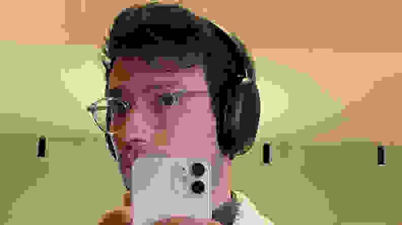 Person taking a mirror photo with smartphone while wearing the Sonos Ace headphones on ears.