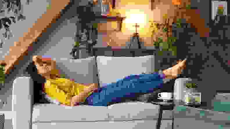 a woman sleeps on her couch with a cup of coffee nearby