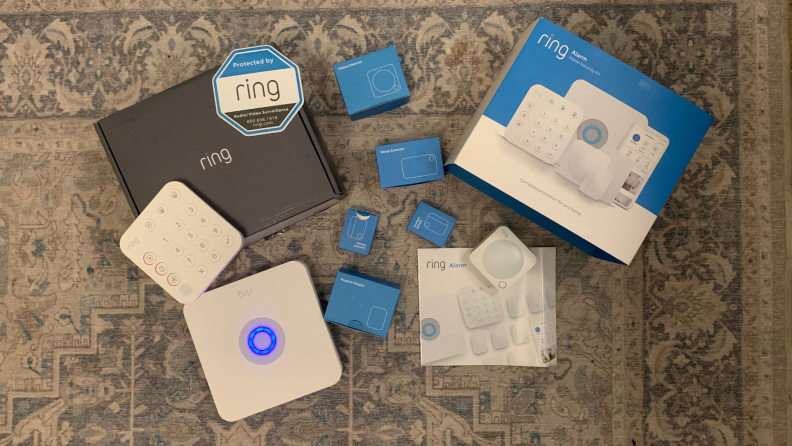 The components of the 5-piece Ring alarm system spread out on a rug.
