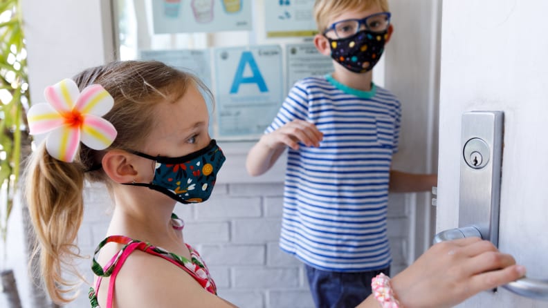 A boy and a girl wearing face masks standing outside a store