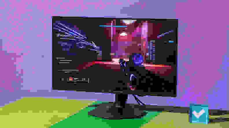The Alienware AW2523HF gaming monitor on top of green and yellow surface in front of purple wall with display featuring interactive video game on screen.