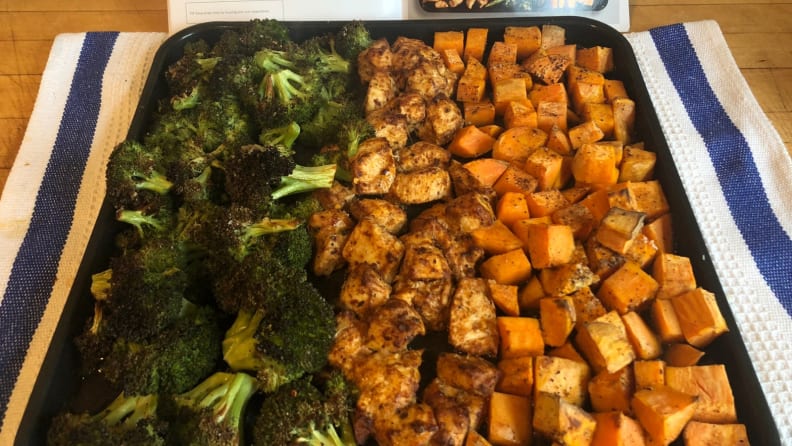 A sheet pan full of roasted vegetables: broccoli on the left and sweet potatoes on the right.