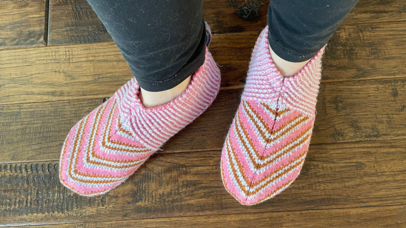 Person wearing two pink Bombas slippers.