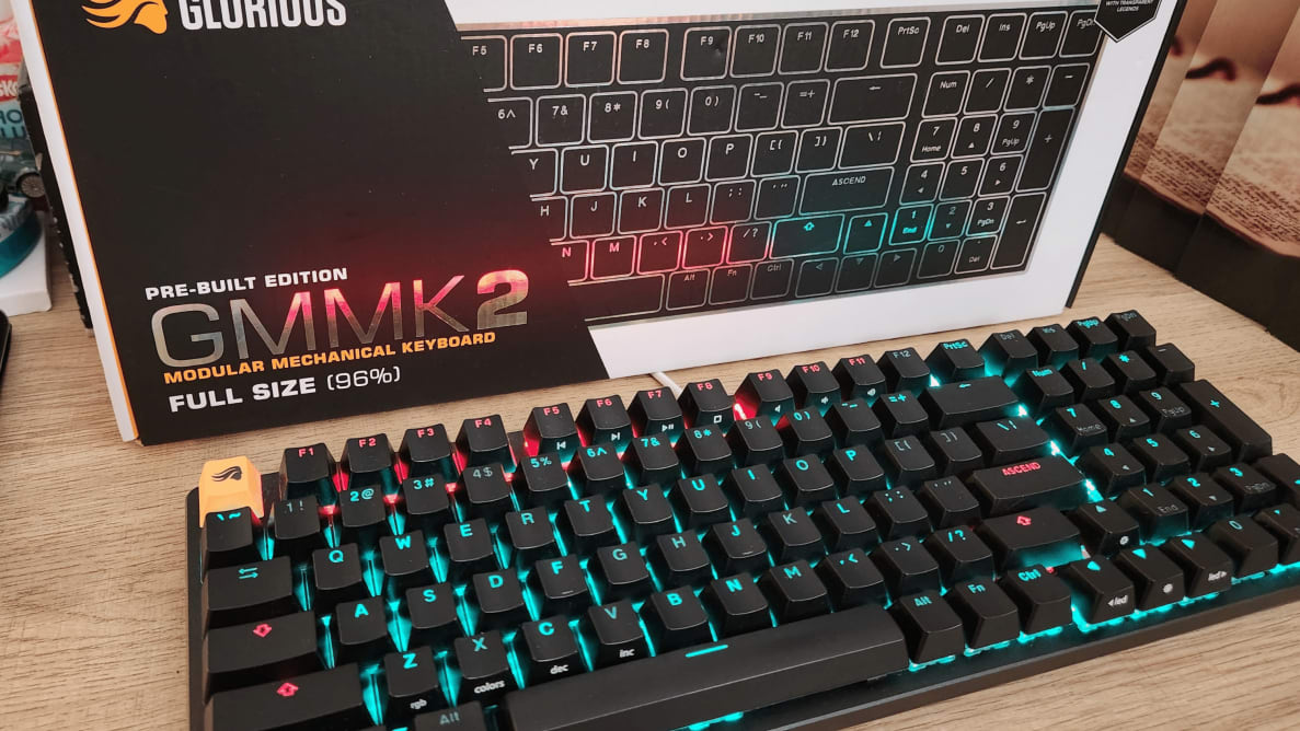 black keyboard in front of a box of the keyboard with blue and red lights underneath the keys