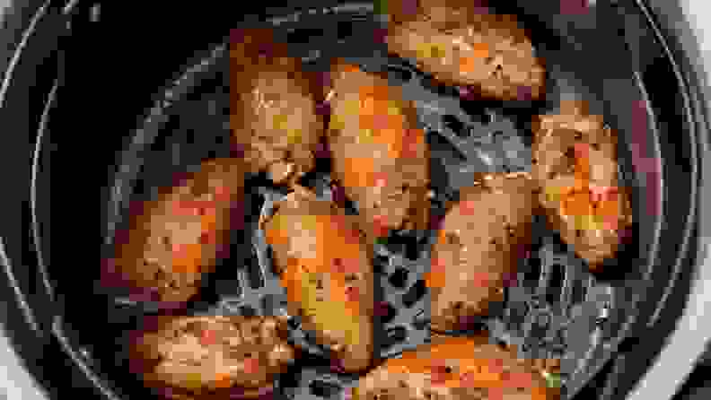 An overhead shot of crispy brown chicken wings in the basket of an air fryer.