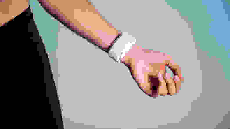 A person wears a white stress tracker on their wrist.